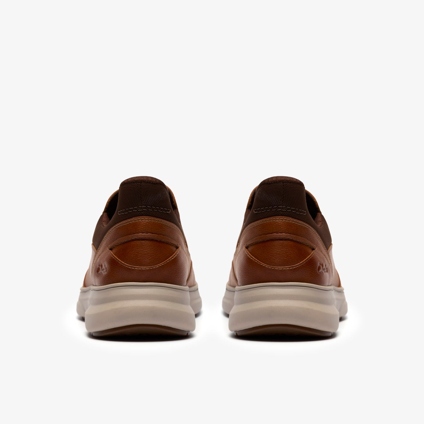A pair of brown leather shoes with a beige sole, rear view.
