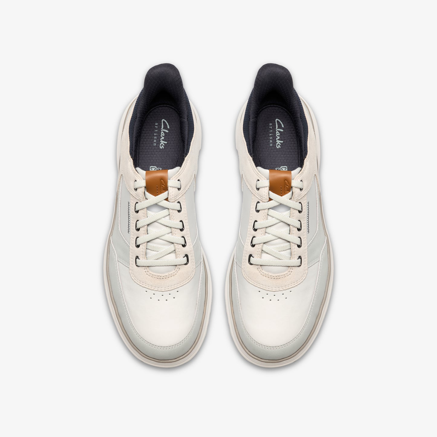 Pair of sneakers, top-down view, white with leather laces, dark inner lining and the word "Artisan" on the tongue.