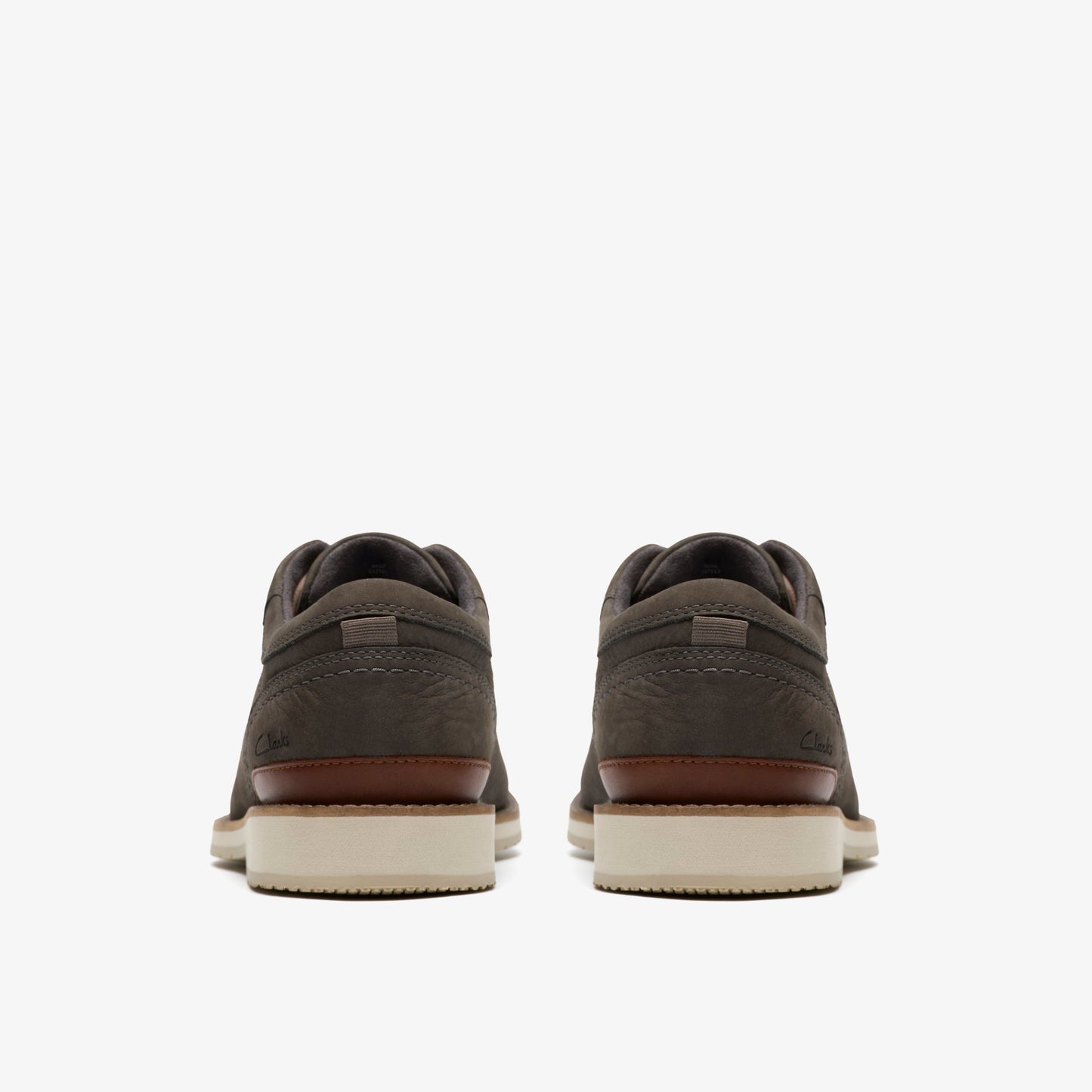 Pair of grey suede shoes with brown accent and white soles, viewed from the back.