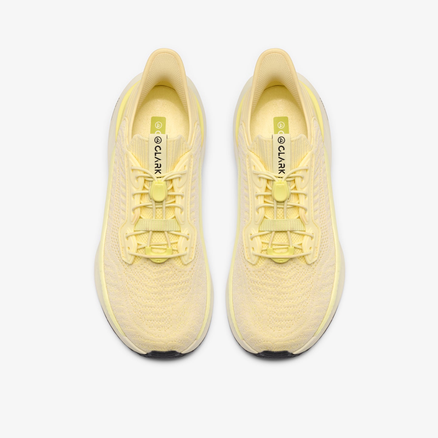 Pair of light yellow running shoes, seen from above, with visible lacing system and "CLARK" text on the tongue.