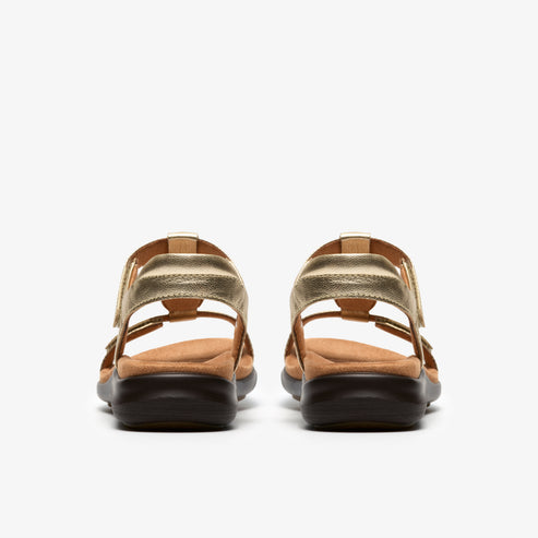 Rear view of gold sandals with adjustable straps and low, dark soles.