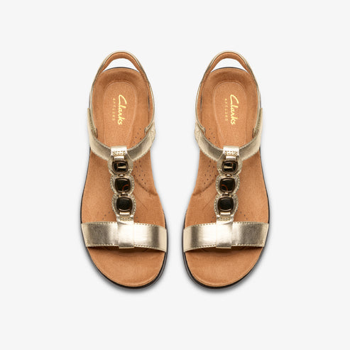 Pair of gold t-strap sandals with dark jewels.