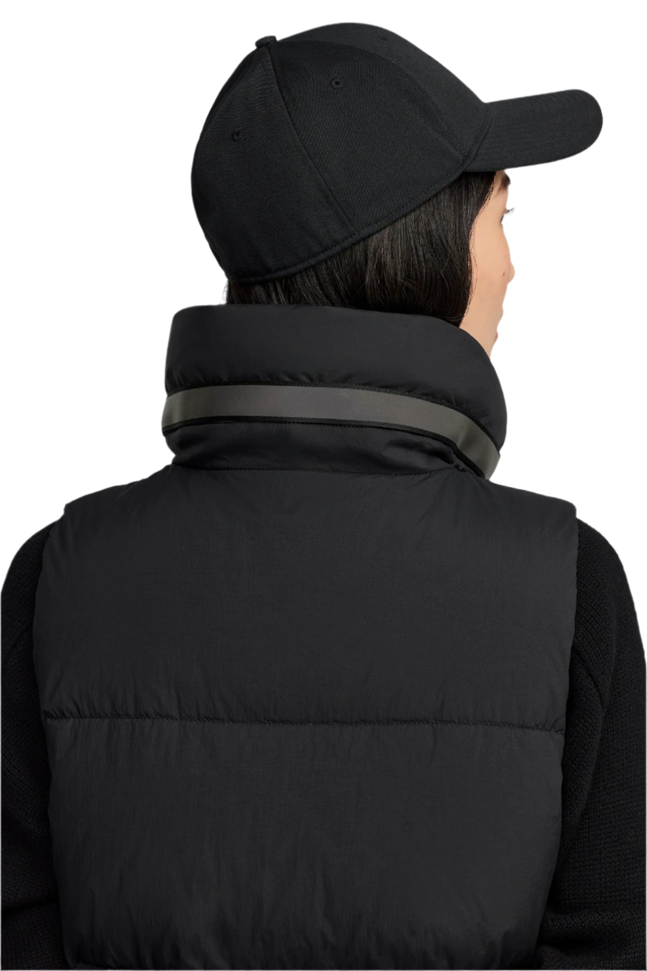 A person wearing a black baseball cap and black puffer vest seen from the back.