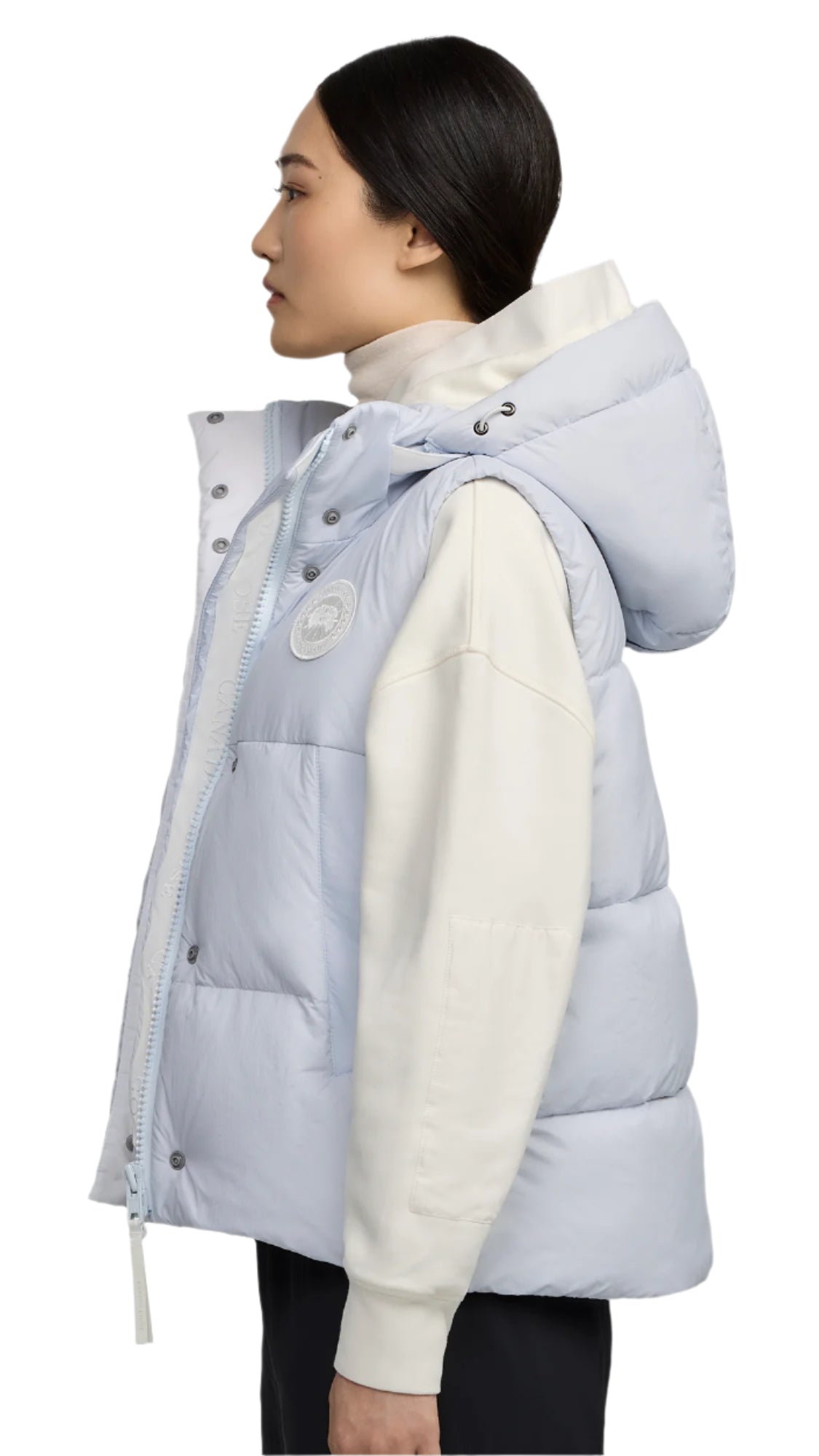 Light blue, hooded puffer vest worn over a cream-colored sweater.