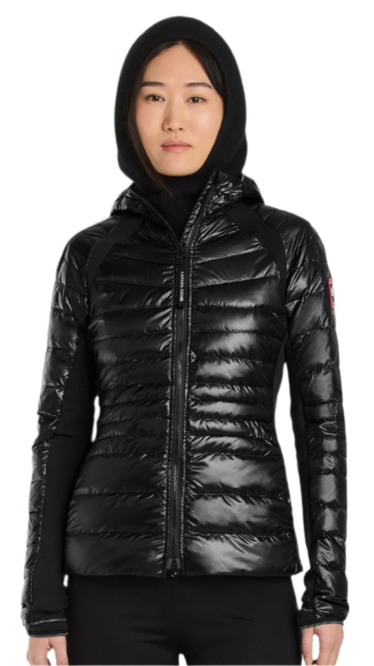 A woman is wearing a black hooded puffer jacket with knit sleeves.