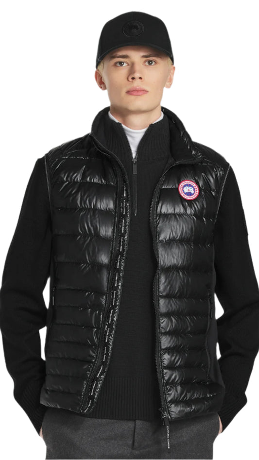 A man wearing a black puffer vest with the Canada Goose logo on the left chest.