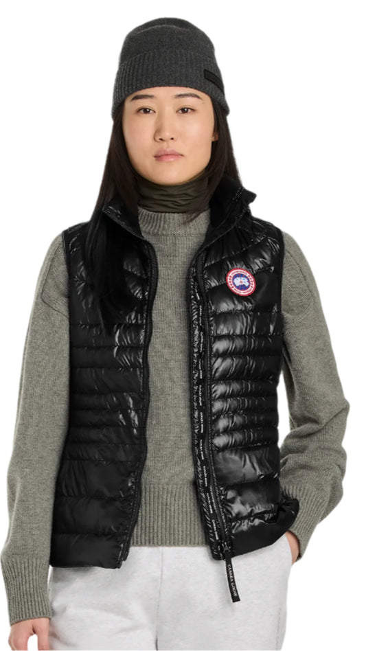 A person wearing a black puffer vest over a grey turtleneck sweater, along with a grey knit beanie.