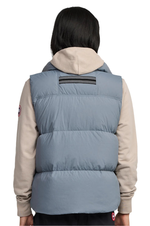 A gray puffer vest worn over a beige hoodie.