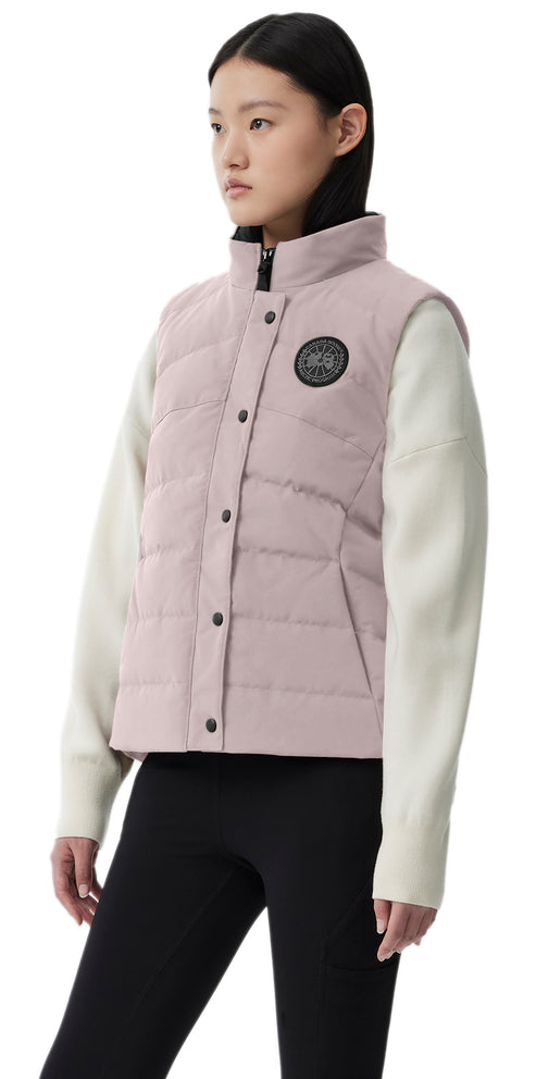 A woman in a pink vest with black leggings and white sleeves.