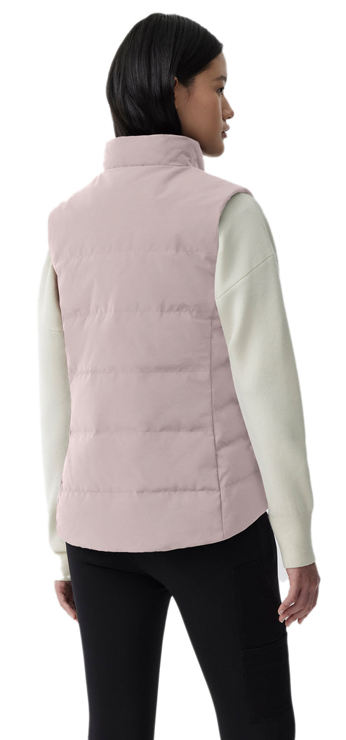 A light pink quilted vest is paired with a long-sleeved, off-white sweater and black leggings.