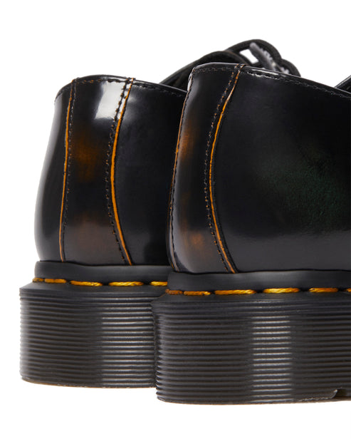 Close-up of the rear of black dress shoes with yellow stitching along the soles.