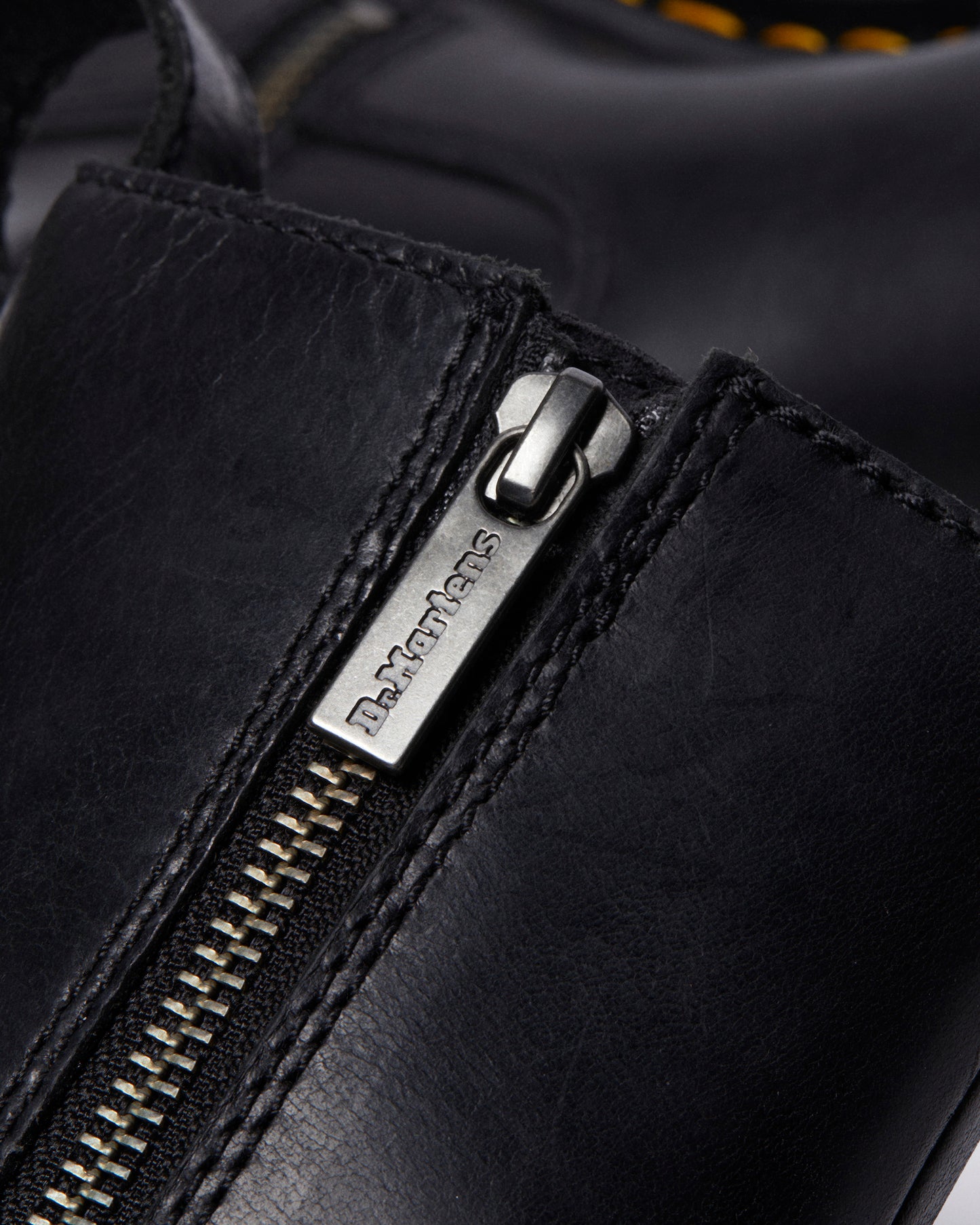 Close-up of a black leather boot with a silver zipper pull that says "Dr. Martens".