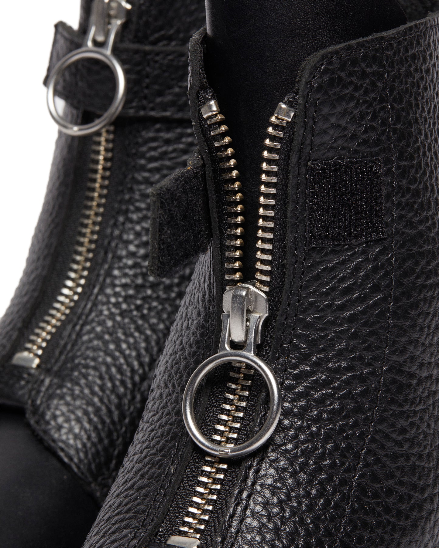 Close-up of black leather ankle boots with front zippers and circular pull tabs.