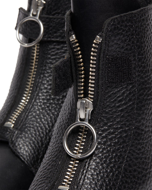 Close-up of black leather ankle boots with front zippers and circular pull tabs.