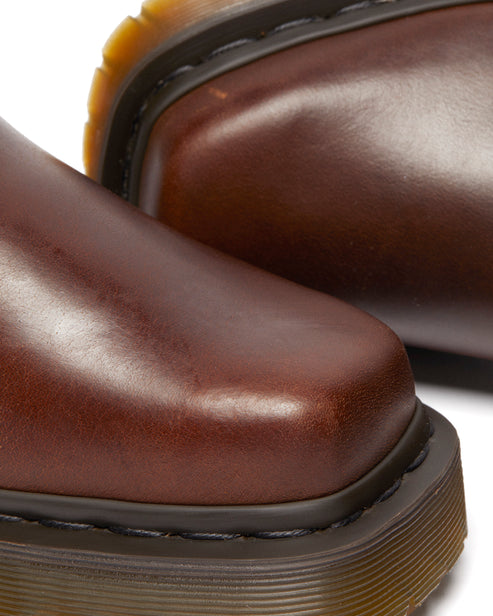 Close-up of brown leather shoes featuring a square toe and prominent black stitching.