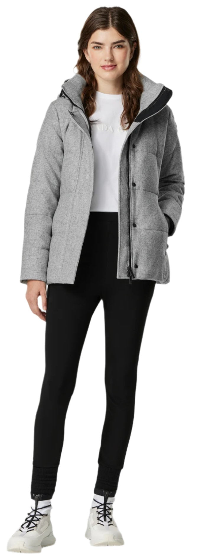 A woman wearing a gray jacket, black pants, and white sneakers.