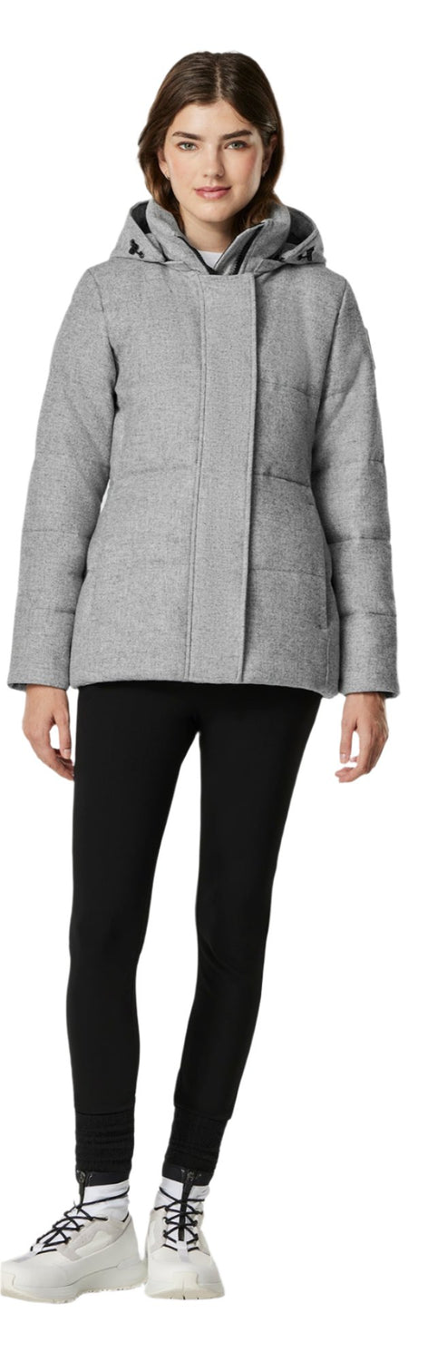 A woman wearing a gray puffer coat with a hood, black leggings, and white shoes.