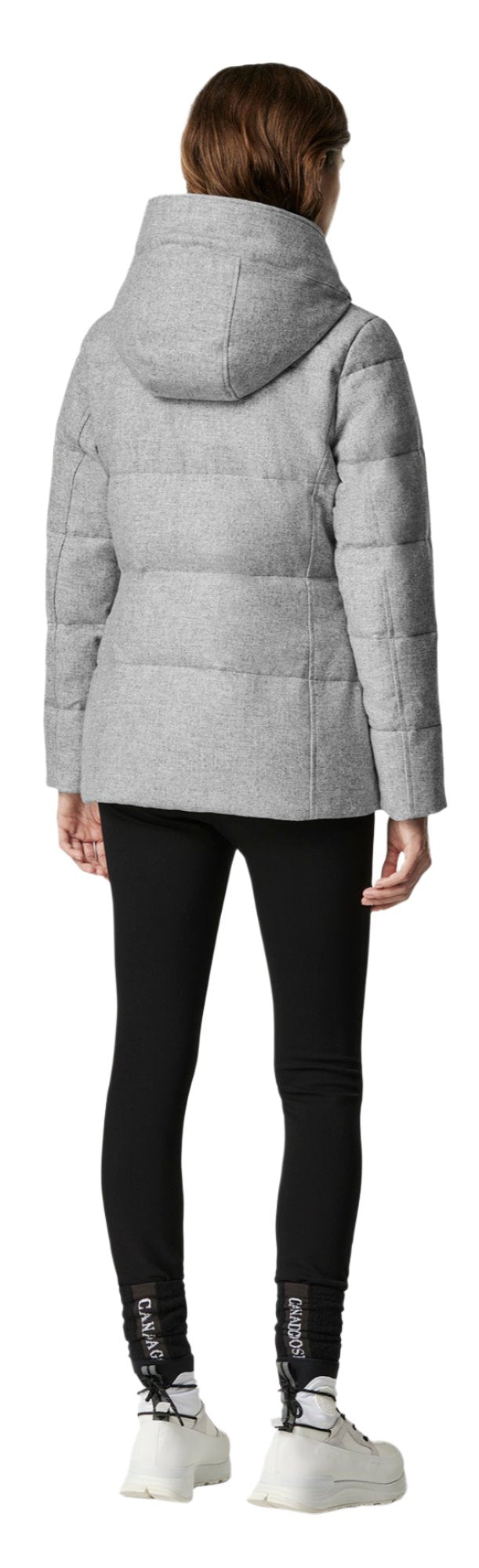 A woman is wearing a grey jacket, black leggings, and white shoes.