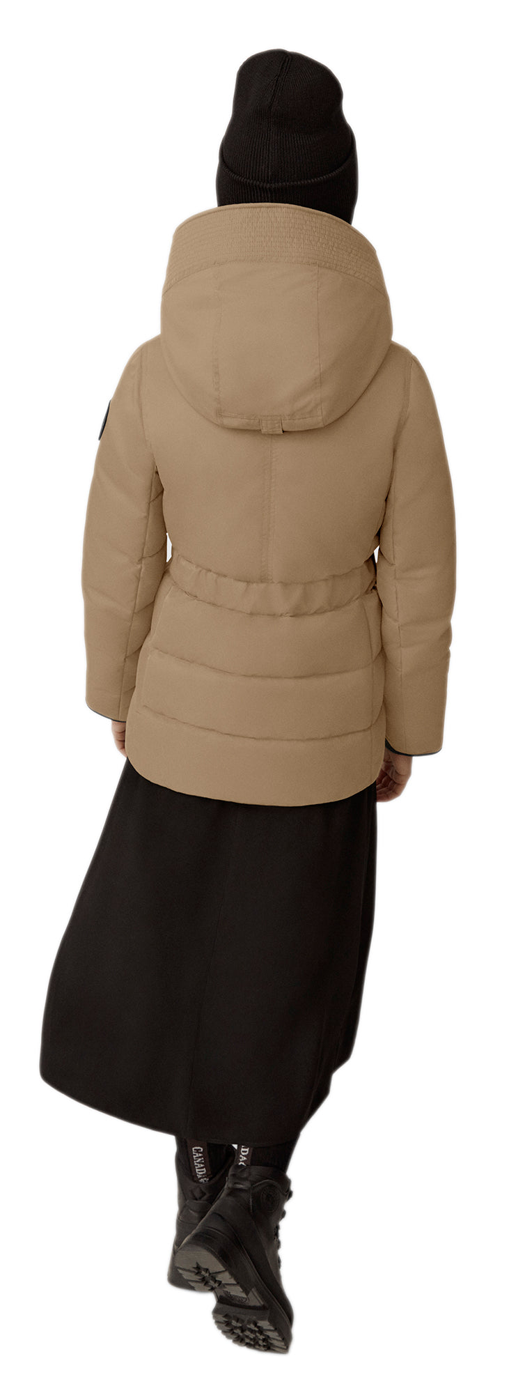 A person facing away wearing a black beanie, a tan puffer jacket, a black skirt, and black boots.