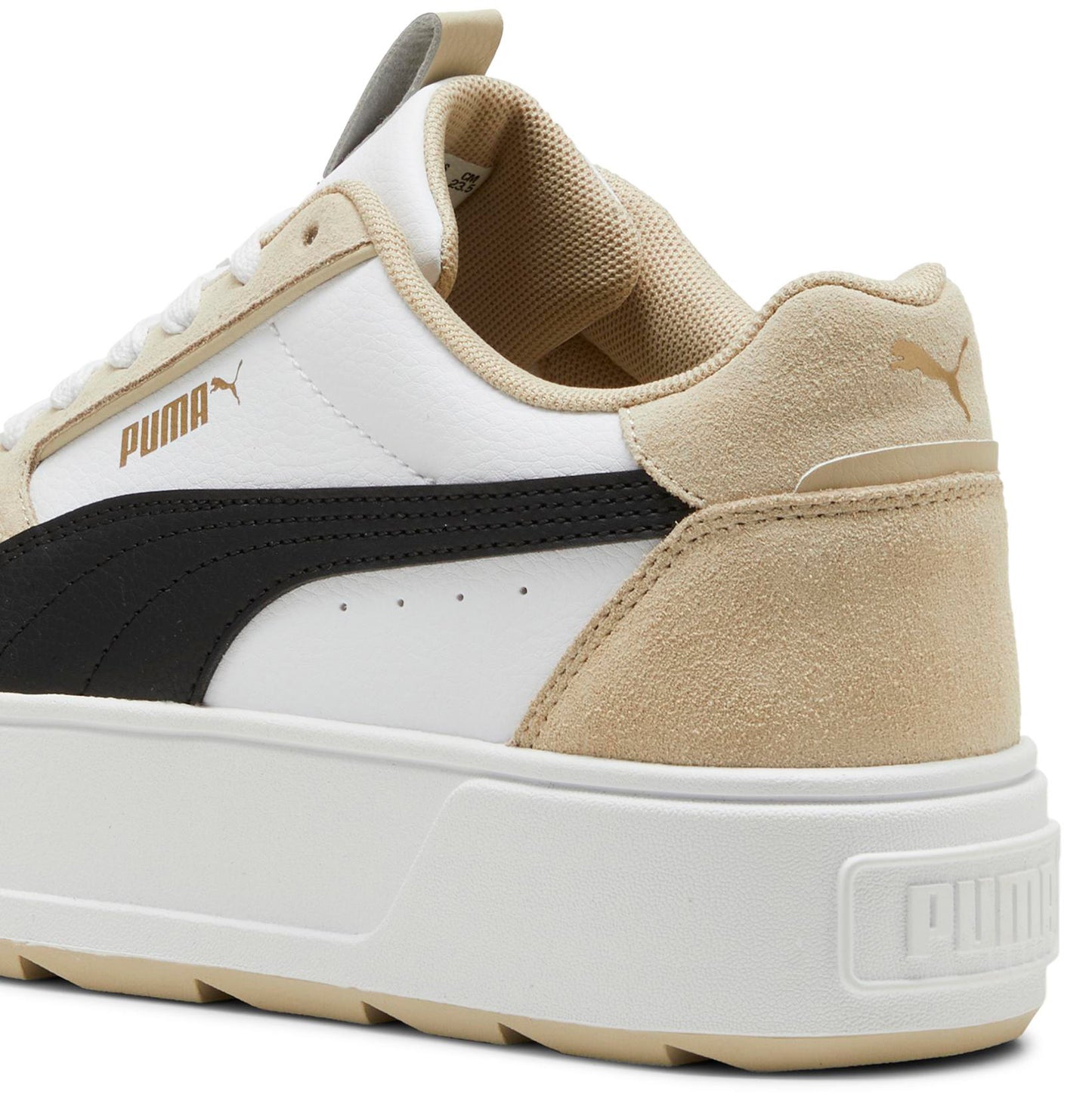 Close-up of a white sneaker with a thick white sole, a black stripe, and a beige suede heel.