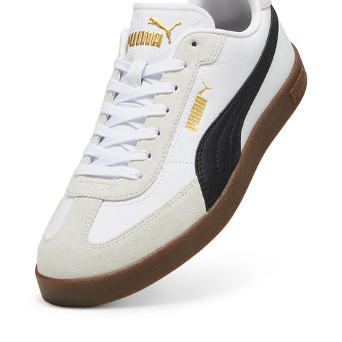 Low top white sneaker with suede toe cap, gum sole, gold logo on the tongue and quarter, and black side stripe.