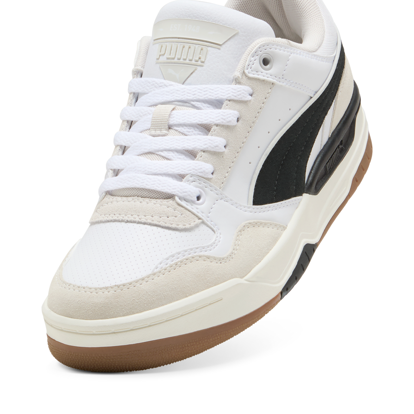 Low-top sneaker featuring white laces, a white leather upper with suede overlays, and a black stripe detail on the side, atop a brown rubber outsole.