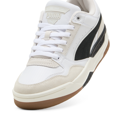 Low-top sneaker featuring white laces, a white leather upper with suede overlays, and a black stripe detail on the side, atop a brown rubber outsole.
