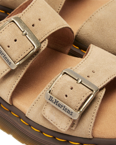 Close-up of suede sandals with adjustable straps and branded metal buckles.