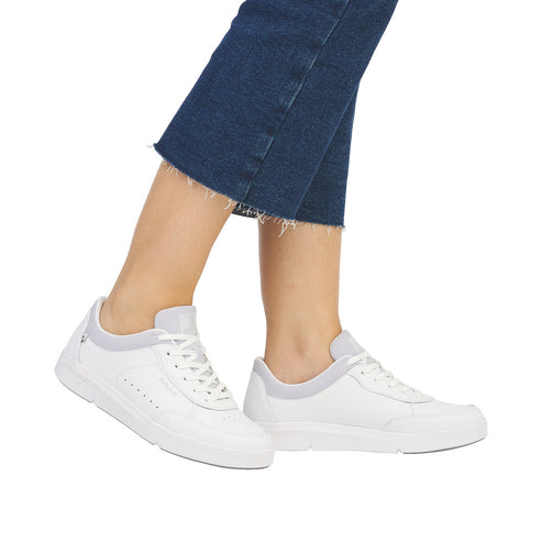 Person wearing white sneakers and dark-wash denim cropped pants.