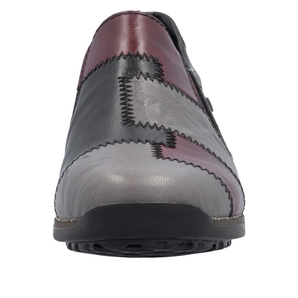 Slip-on shoe featuring a colorful patchwork design with colors of red, gray, and black.