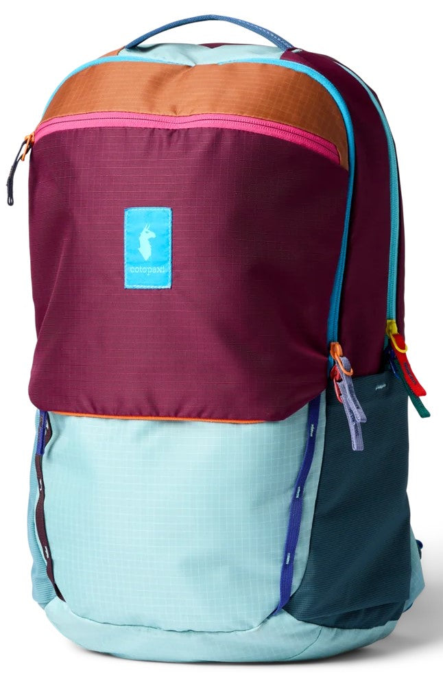 A colorful backpack featuring a light blue bottom section, a dark maroon top section with a tan accent band at the very top, and a light blue rectangular logo patch with a llama icon. The bag has a light blue carrying handle, bright pink zipper accents, and side pockets in dark teal and light blue.