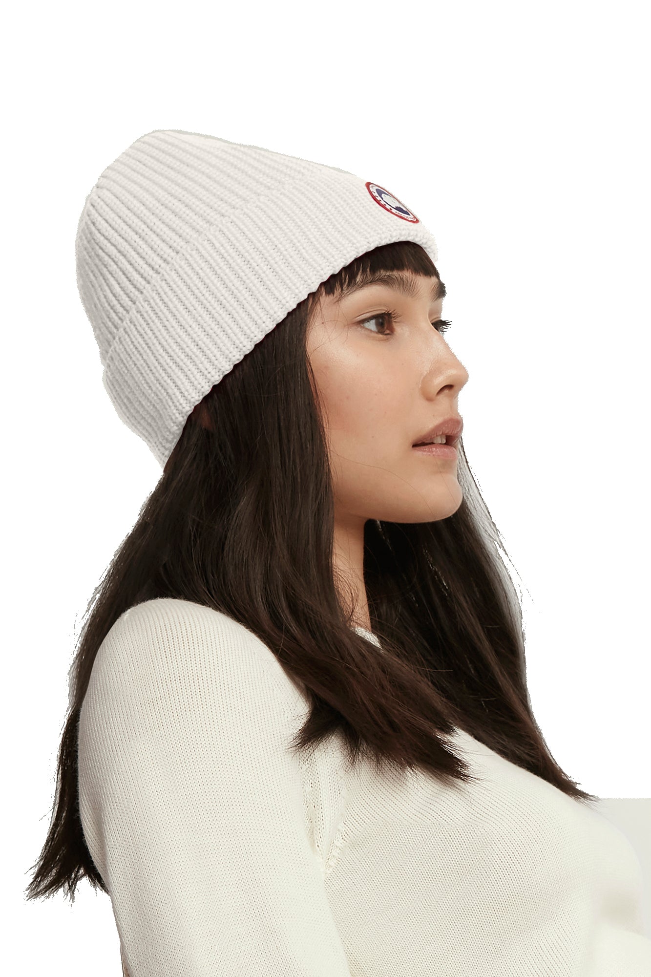Woman wearing a white ribbed beanie with a round logo on the side.