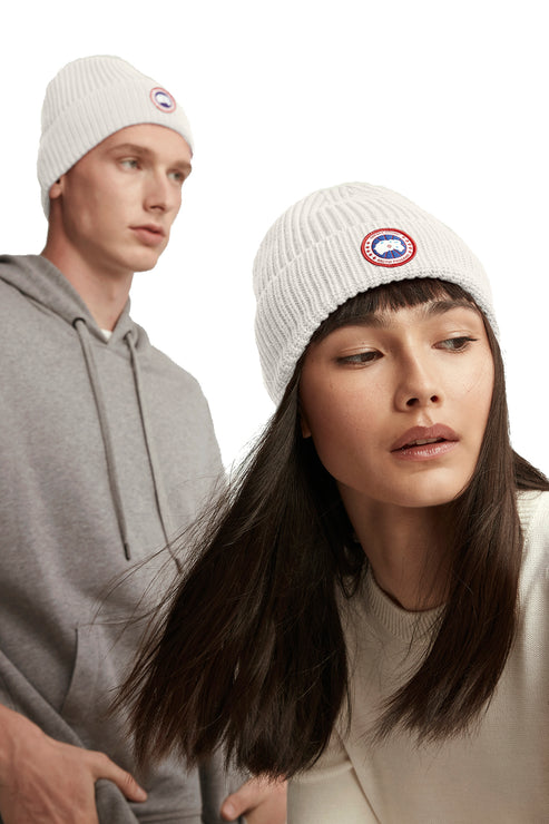 Two people wearing white beanies with a circular logo.