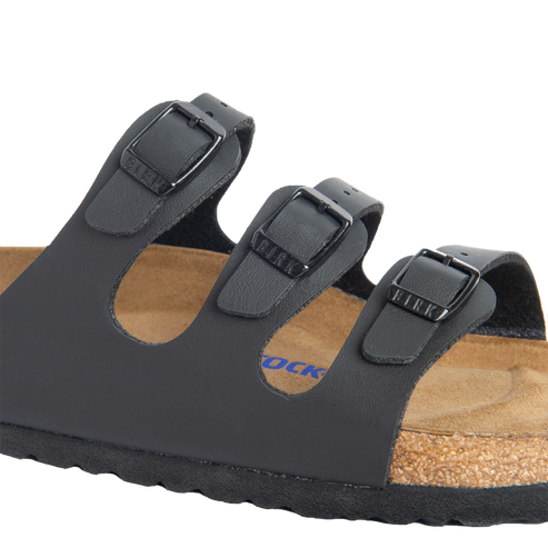 Close-up of a black sandal with three straps and adjustable buckles.