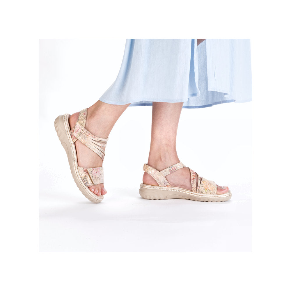 Ankle strap sandals with crisscrossing straps in gold on a foot.