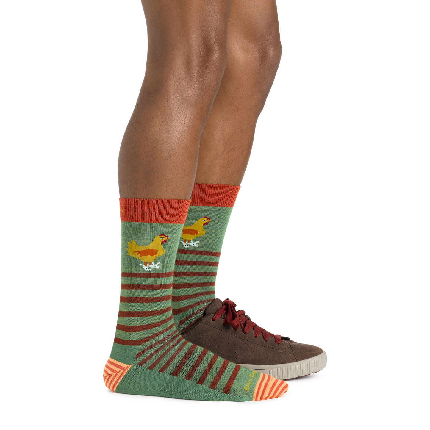 Legs wearing patterned socks and brown sneakers. The socks are green with brown stripes and a cartoon chicken.