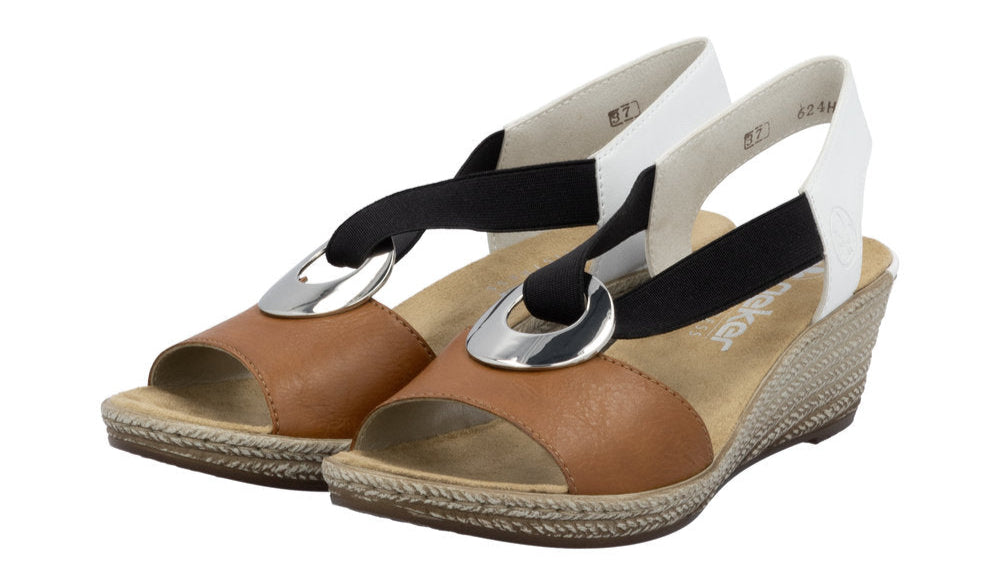 Pair of tan and gold wedge sandals with black and white elastic straps and silver ring accents.
