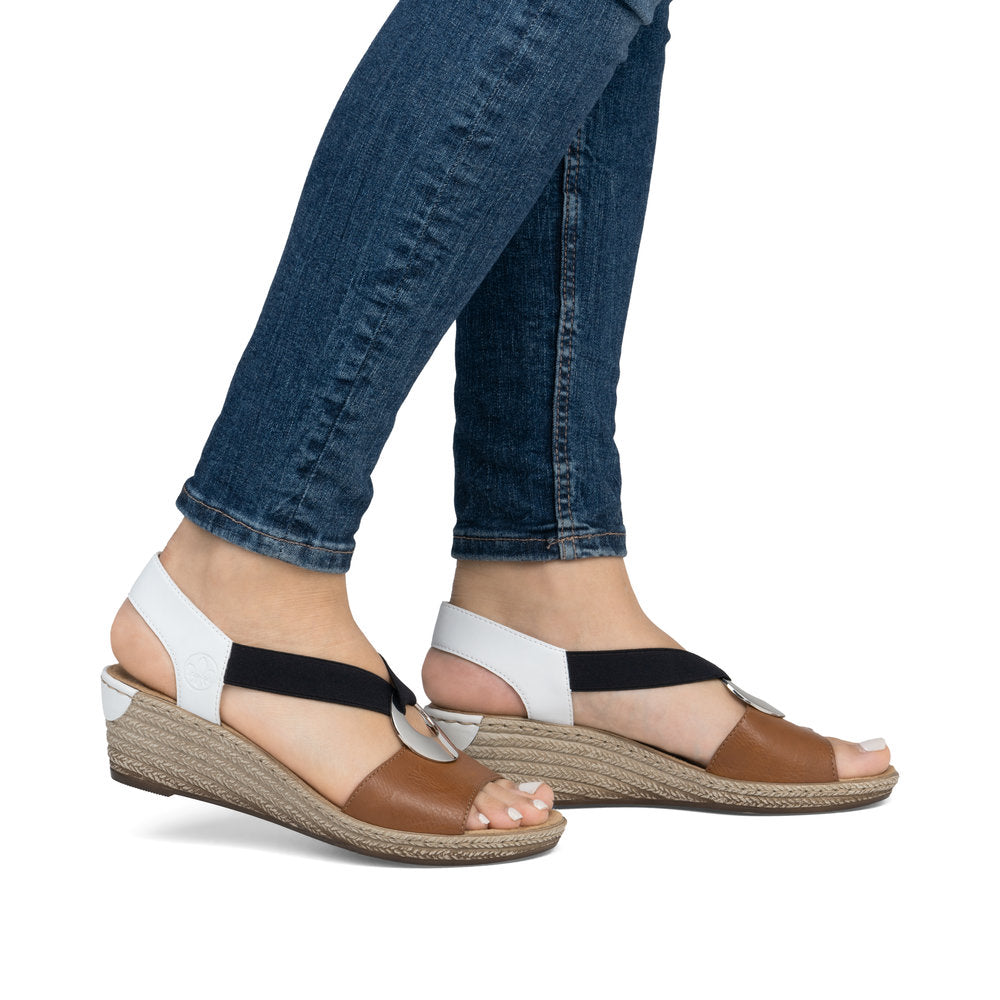 A pair of sandals with brown toe, black and white straps, and wedge heels.
