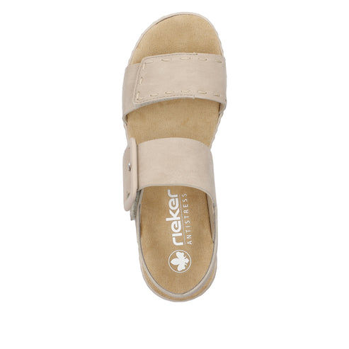 Top-down view of a light beige sandal with two straps, one across the toes and one across the instep, with the word "rieker ANTISTRESS" printed on the footbed.