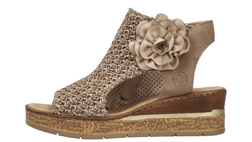 Beige sandal with open toe, woven top, large flower embellishment, and wedge heel.