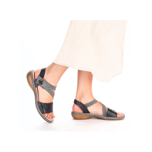 A pair of black sandals with elastic gray straps being worn.