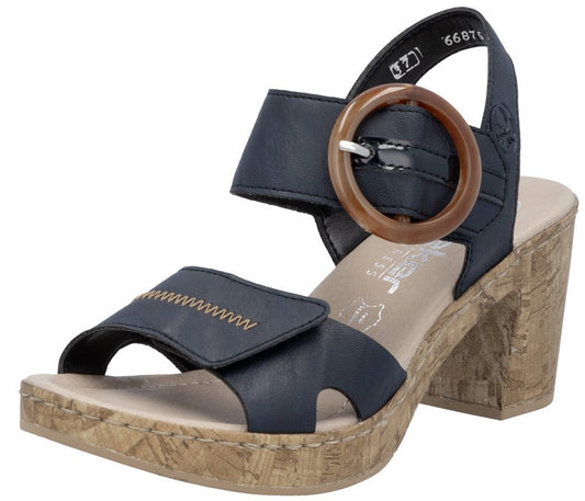 Dark blue heeled sandal with decorative circular buckle and textured cork sole.