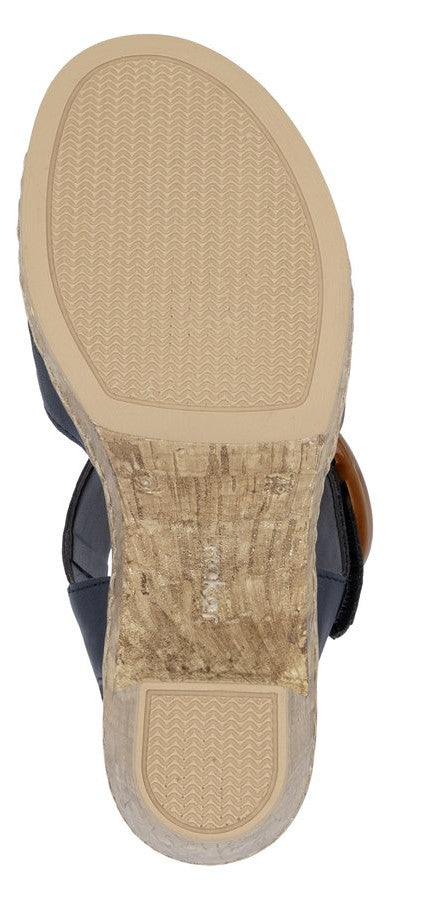 Bottom view of a sandal with a textured tan sole and a chunky cork heel.