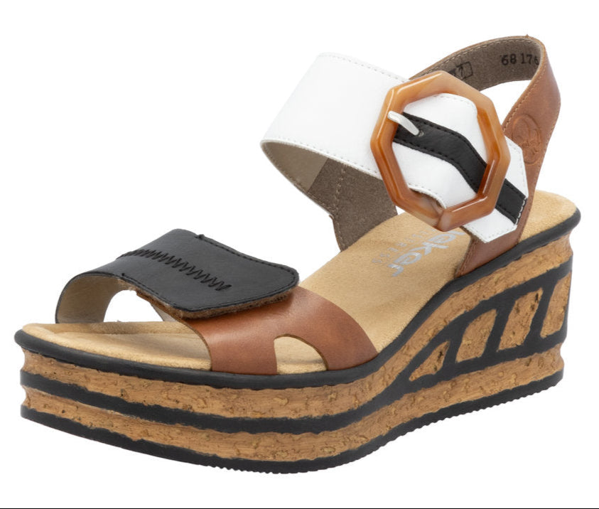Platform sandal with a thick cork-like sole, brown and black straps, and a white ankle strap with an oversized buckle.