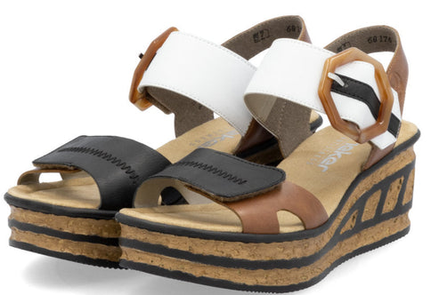 A pair of platform wedge sandals, one with a black toe strap and white ankle strap with a decorative buckle and the other with a brown toe strap and brown and white ankle strap with a decorative buckle.
