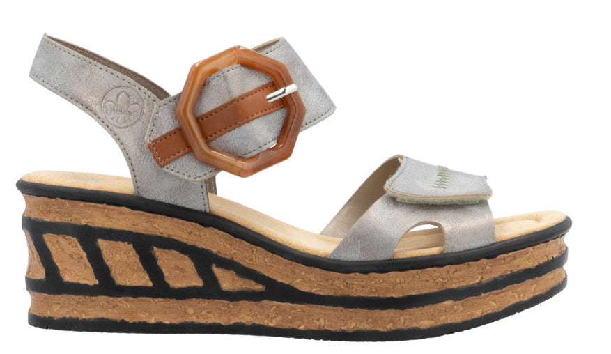 Metallic silver sandal with a chunky cork platform and black accents; velcro straps include a decorative brown buckle.