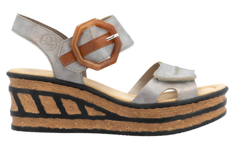 Metallic silver sandal with a chunky cork platform and black accents; velcro straps include a decorative brown buckle.