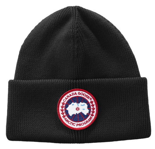 Black knit beanie hat with a circular patch of a map inside a red circle with text 'CANADA GOOSE ARCTIC PROGRAM'.