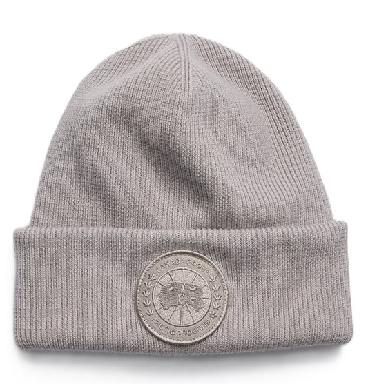 Gray knit beanie with circular logo patch.