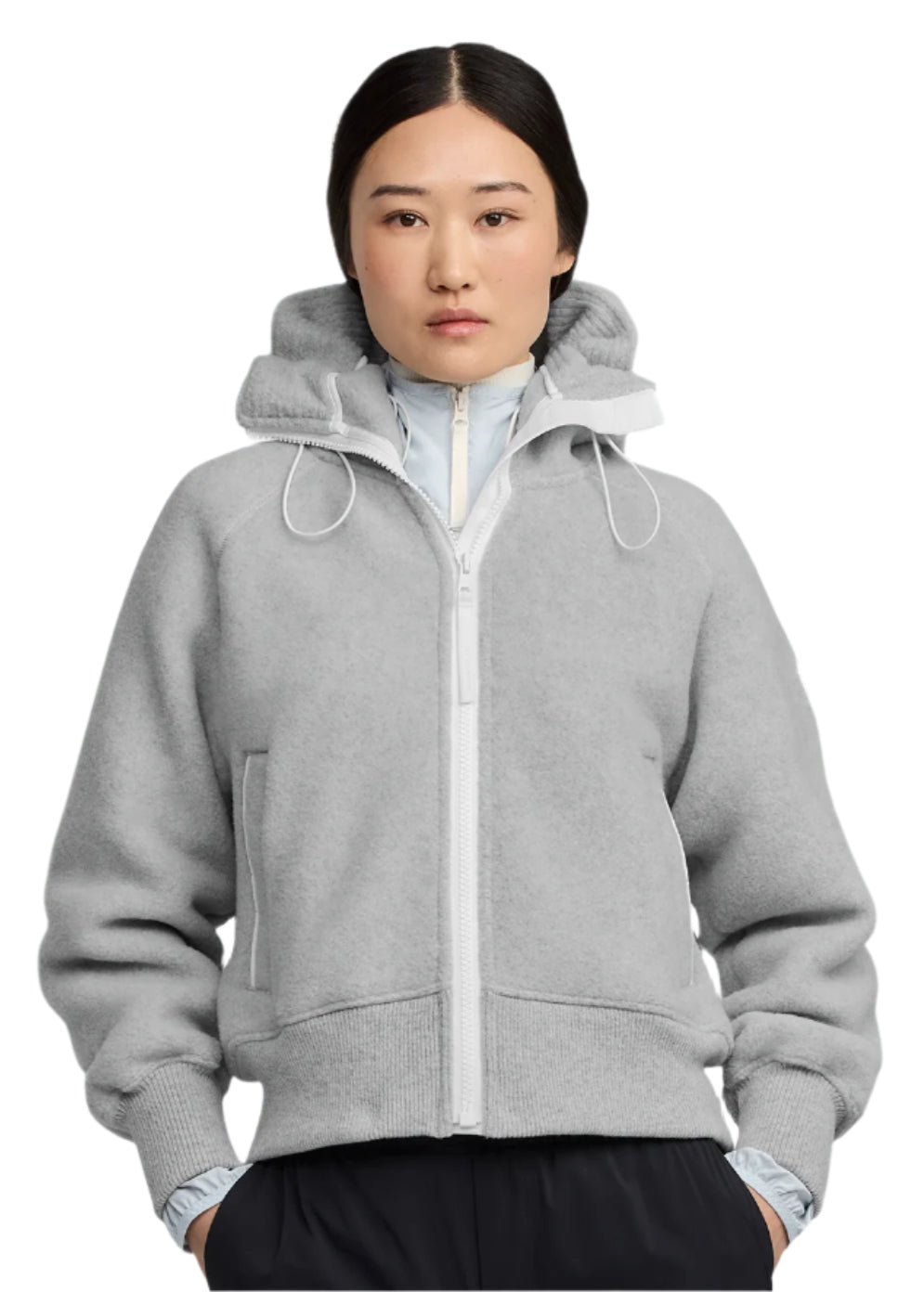 A woman wearing a light gray, hooded zip-up jacket.